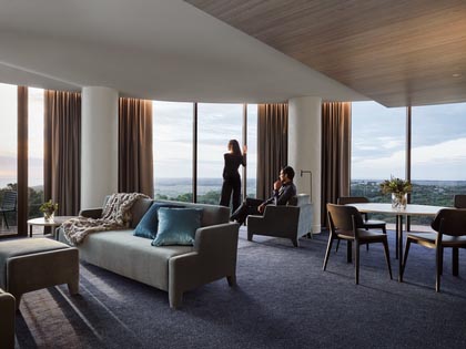 Couple relaxing in the RACV Cape Schanck Peninsula Suite, overlooking the beautiful room views from the expansive windows. 