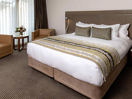 Large bed with chairs and bedside table.