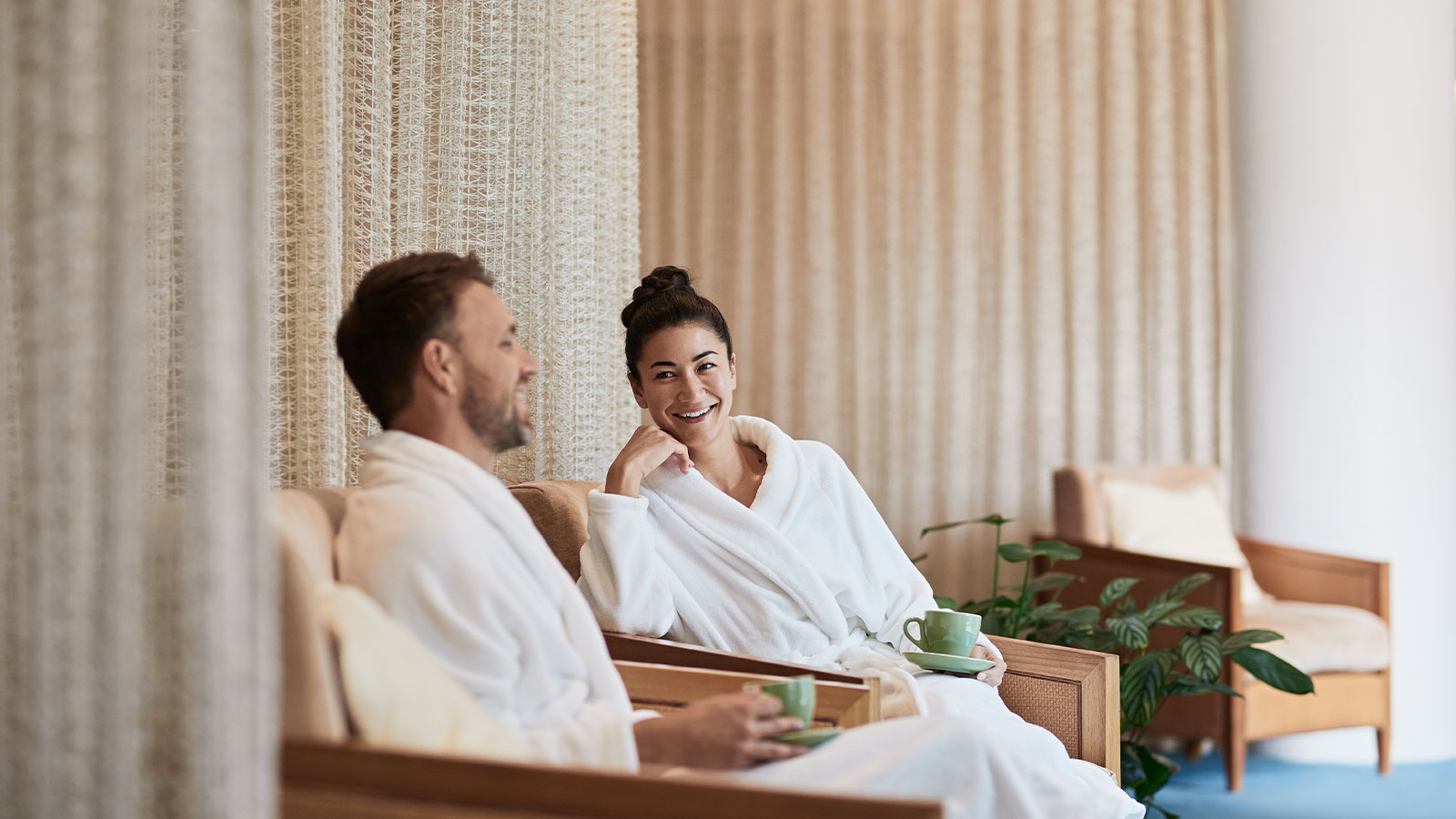 Couple sitting in bathrobes and drinking tea at the RACV Healesville Country Club & Resort's One Spa lounge.