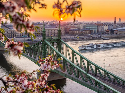 European city at sunset with a cruise ship going down a river