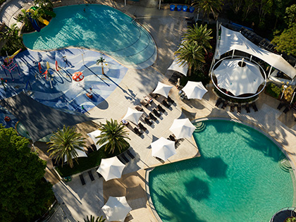 Royal Pines outdoor pool area, including lagoon pool, water park and green palm trees.