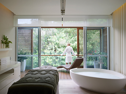 Person in bathrobe looking out balcony in a treatment room at RACV Royal Pines One Spa.