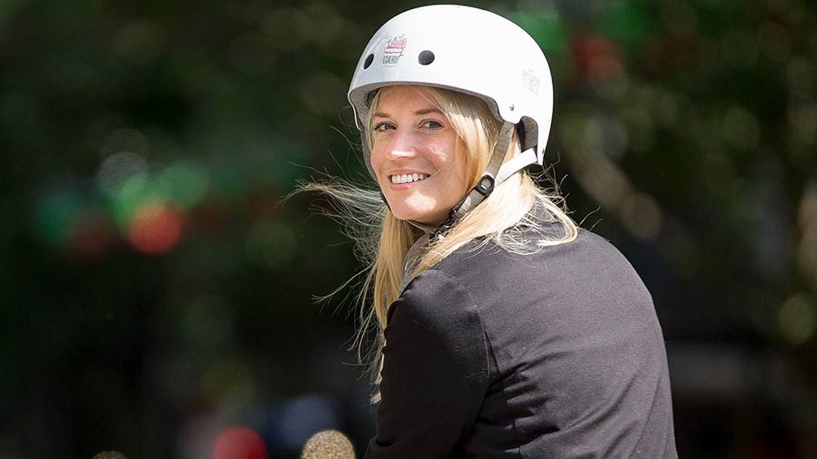 A smiling, young woman wearing a white helmet.