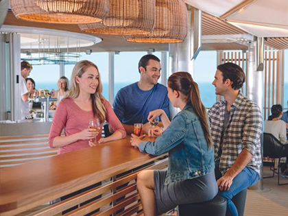 Four people on the Spirit of Tasmania, smiling and talking with drinks in their hand in a bar.