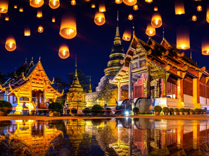 Lanterns in the night sky above traditional Thai temples