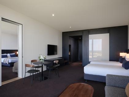 Interconnecting premium ocean view room at RACV Torquay Resort, featuring a king bed, desk and couch.