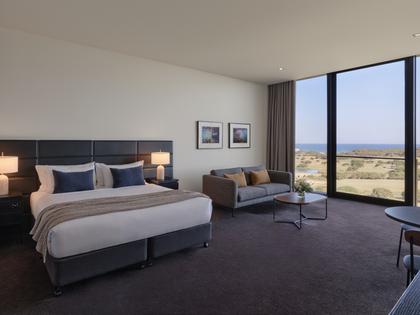 Premium ocean view room at RACV Torquay Resort, featuring a king bed, desk and couch.