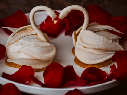A luxurious cake featuring rose petals and sculpted swans