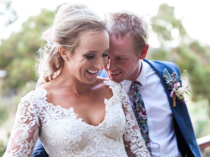 Bride and groom posing in front of greenery at RACV Goldfields resort.