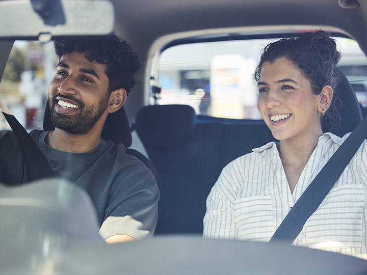 A young couple smiling in their car.