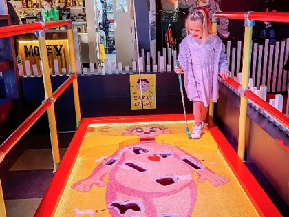 Young girl playing mini golf at Holey Moley